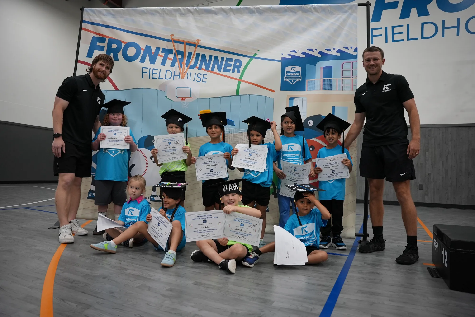 Move & Learn home school athletes celebrating under the Frontrunner Fieldhouse banner
